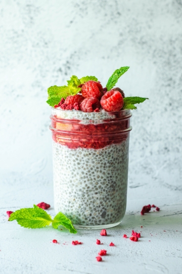 Raspberry Chia Pudding in a glass jar with raspberries on top.