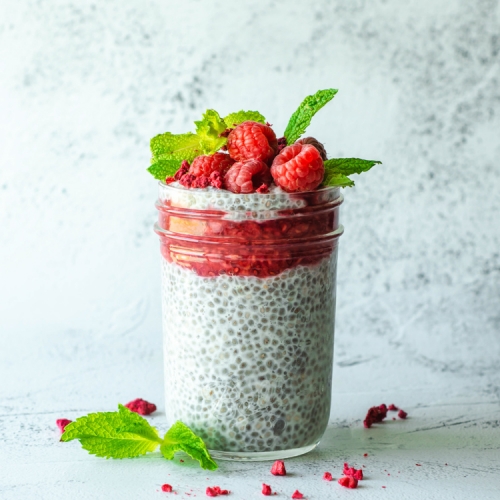 Raspberry Chia Pudding in a glass jar with raspberries on top.