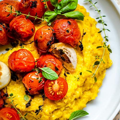 Polenta with roasted tomatoes on white plate