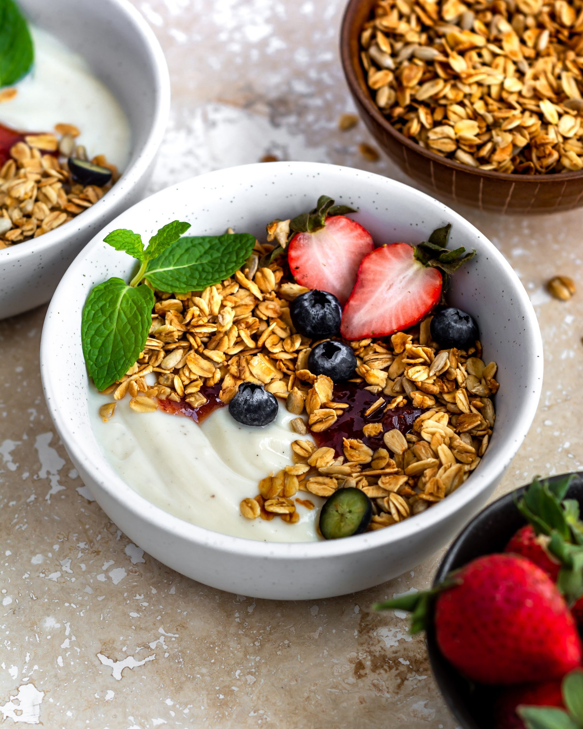 nut free granola in a white bowl with fresh fruits and soy yogurt