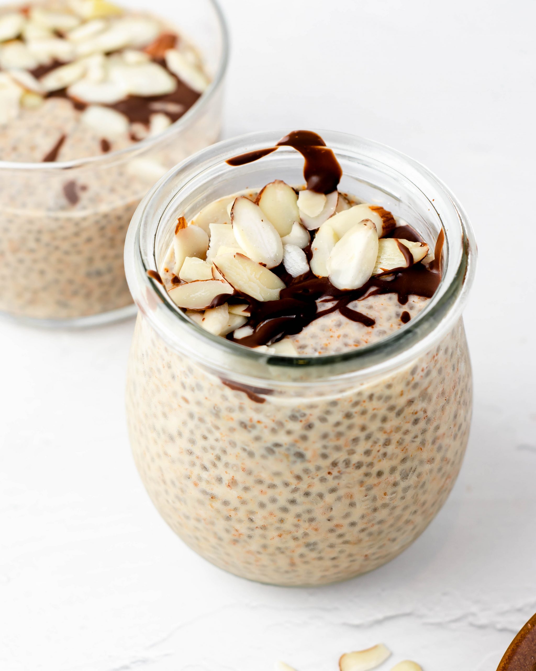 almond butter chia pudding in a jar with melted chocolate and raw almond slices